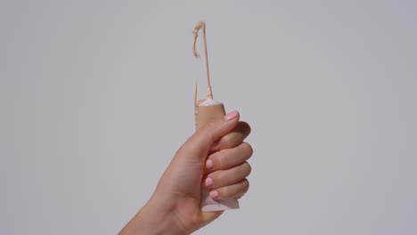 Close-Up-On-Woman-Squeezing-Tube-Of-Make-Up-Until-Contents-Squirt-Out-Shot-On-White-Background